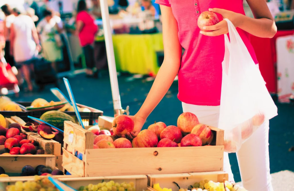 Farmer's Market where someone is deciding on fresh fruit to buy. Keep reading to discover the top things to do in Gainesville.