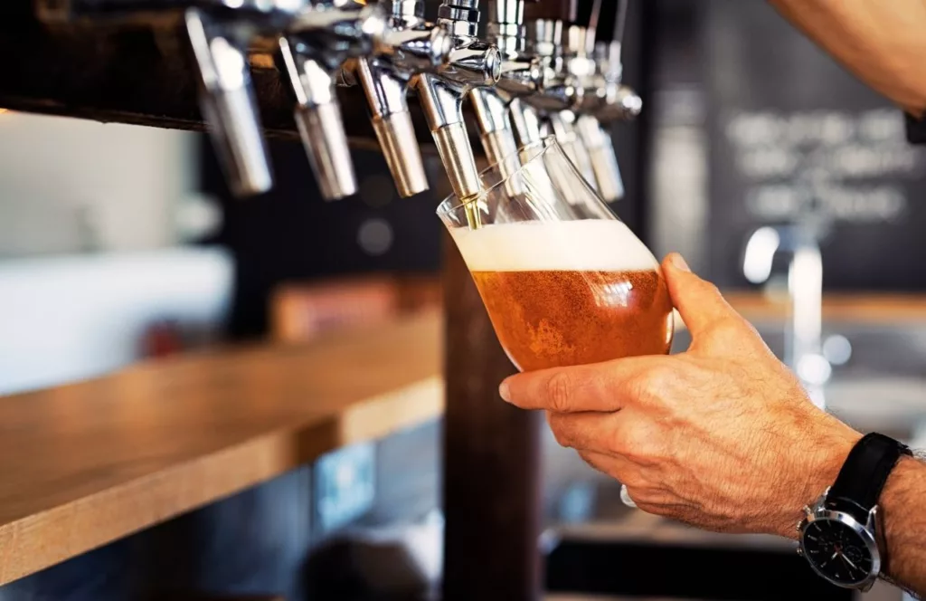 Coppertail Brewing Company with man pouring beer from tap. Keep reading to find out more about the best breweries in Tampa. 