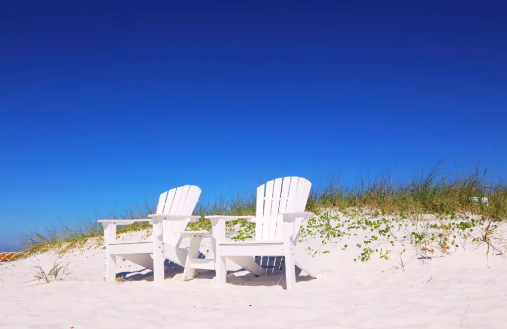 St. Petersburg Beach, Florida with white adirondack style chairs on the beach.  Keep reading to get the best west central Florida beaches.