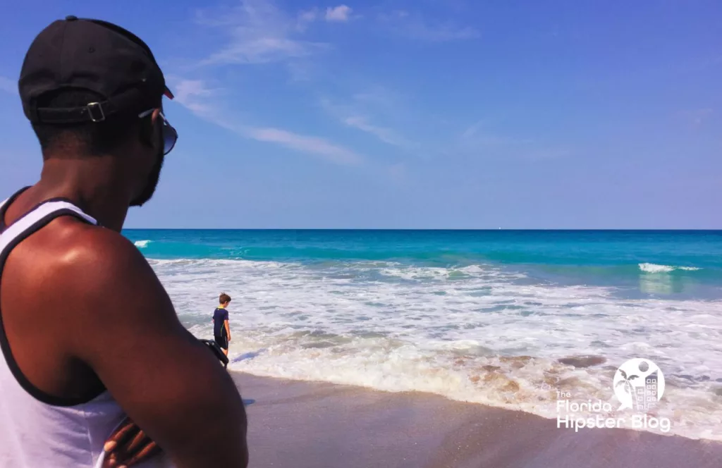 Man looking at the ocean in Jupiter Beach Florida Splashing Rocks. Keep reading to learn about shark watching in Florida and how to avoid attacks.