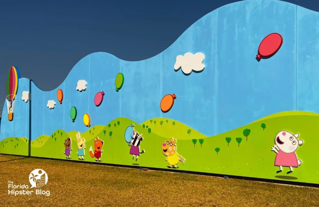 Peppa Pig Theme Park Florida Characters on a wall playing with balloons. Keep reading to find out all you need to know about Peppa Pig Theme Park. 