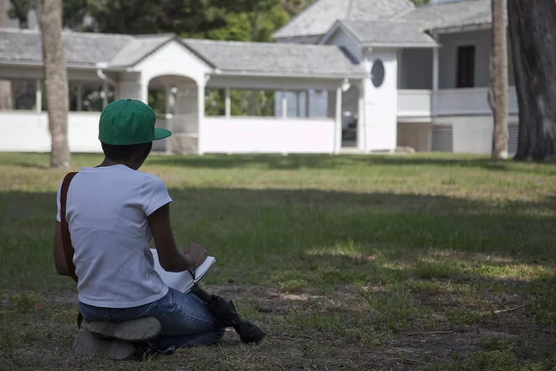 Black lady sitting on grass near the main house at the Kingsley Plantation in Jacksonville, FL. Keep reading to get fun and free things to do in Jacksonville, Florida.