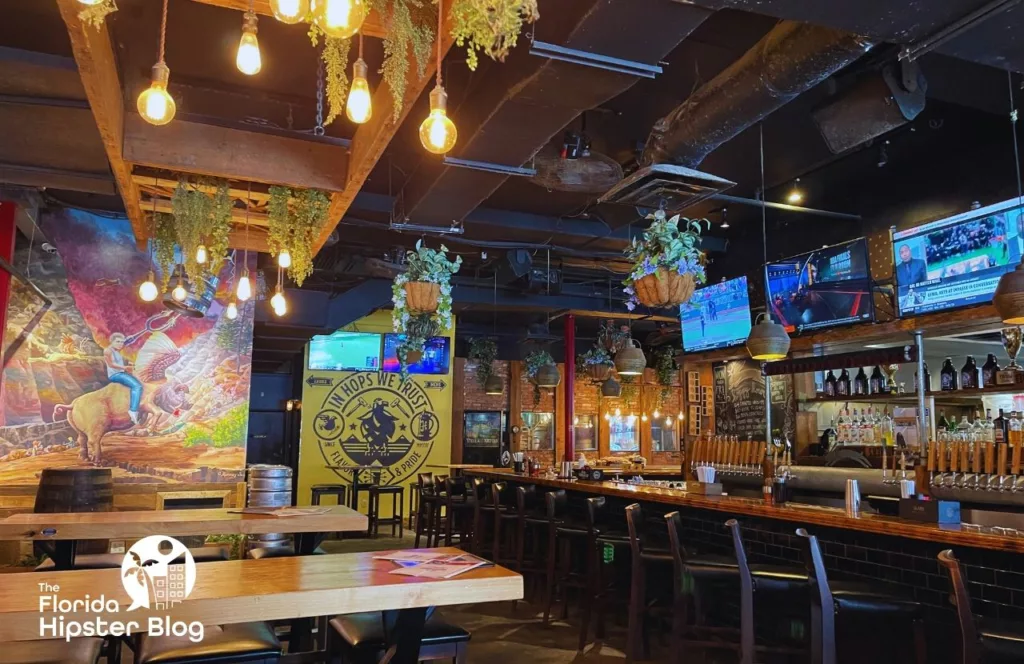 Hoptinger Brewery bar interior with bar area and hanging lighting and plants and colorful artwork. Keep reading to find out all you need to know about the best wings in Jacksonville.