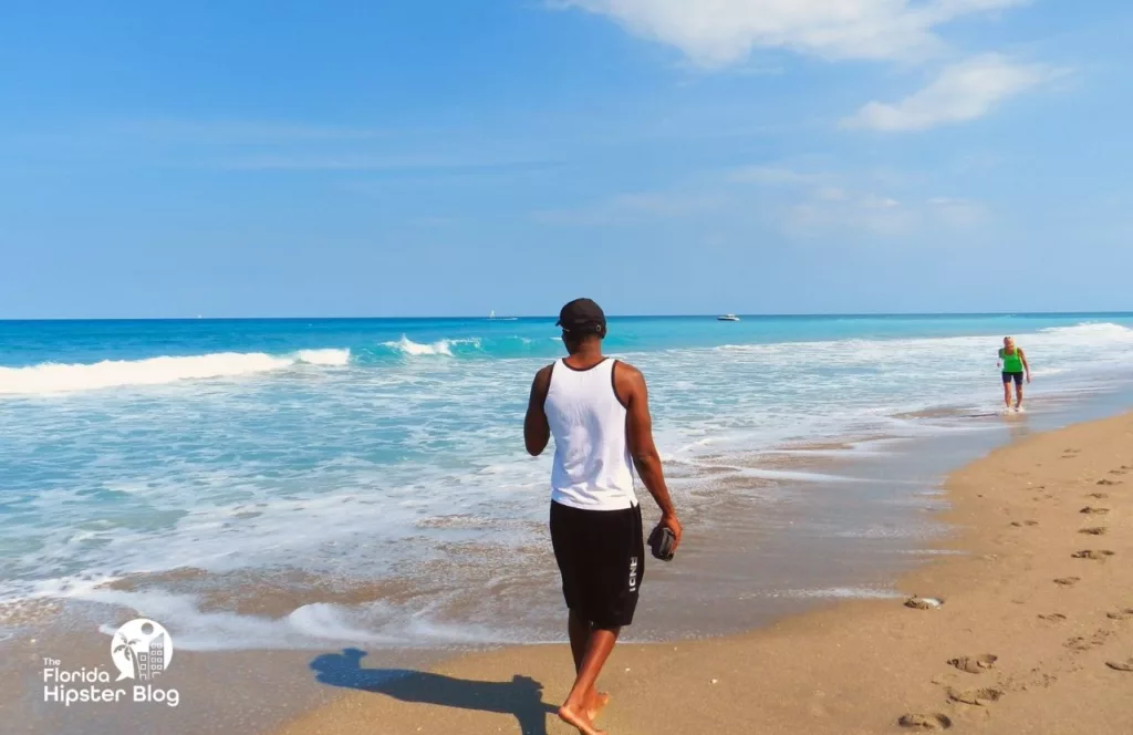 Jupiter, Florida Rocky Beach Shore with black man walking. Keep reading learn about what to pack for Florida and how to create the best Florida Packing List 