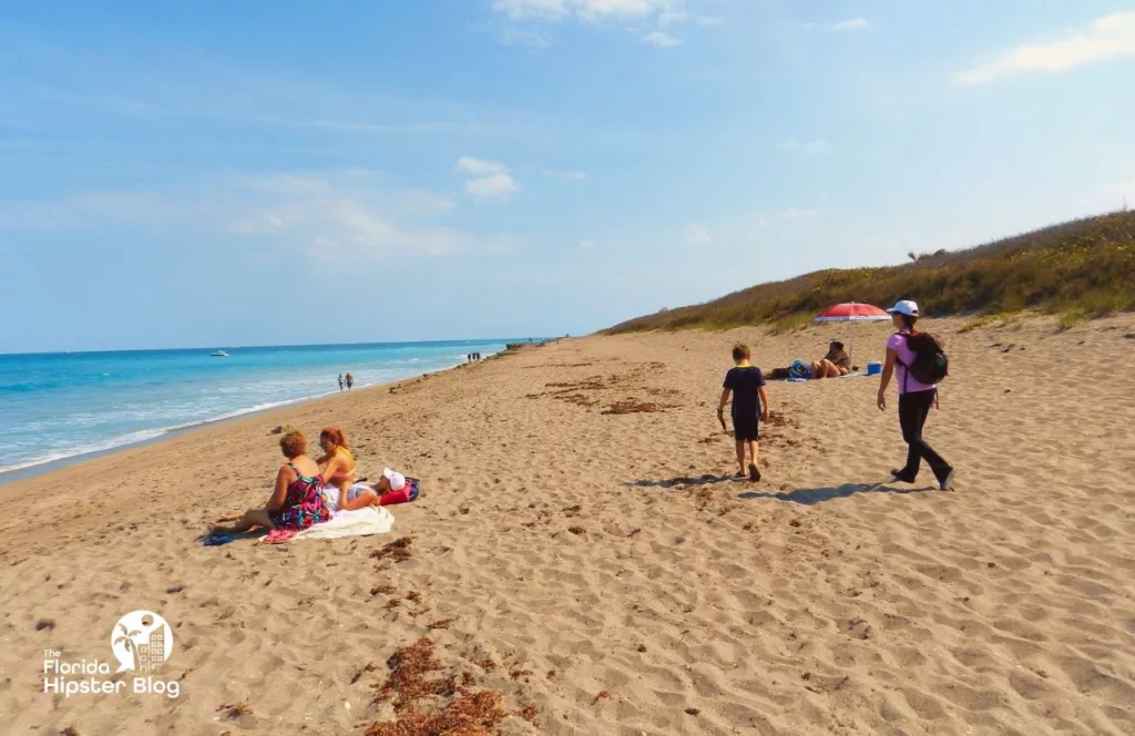 Jupiter, Florida Rocky Beach Shore with people sunbathing on the sand. One of the best things to do in Florida for Memorial Day Weekend.