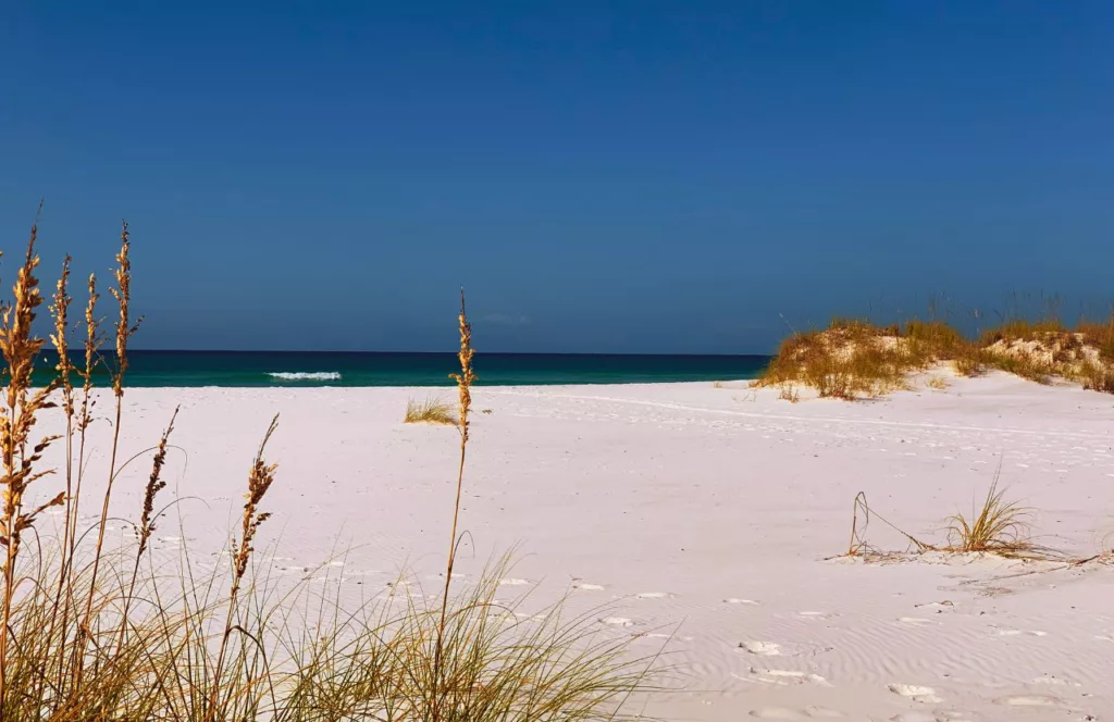 Keep reading to learn about the Best Public Beaches in Destin, Florida.  Eglin Matterhorn Beach with clean which soft sand, bright blue skies and clear turquoise water. 