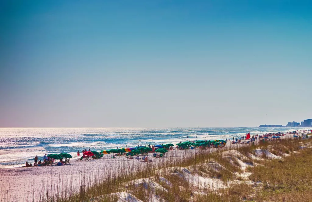 James Lee Park Beach with beach umbrellas and loungers with people out enjoying the sun, and white sand. Keep reading to learn about the Best Public Beaches in Destin, Florida