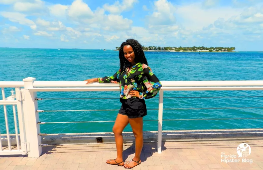 Key West, Florida with NikkyJ in front of the beautiful blue water and ocean. Keep reading to get the best souvenirs from Florida.