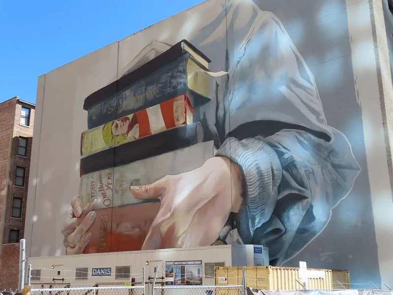 Person holding books on the mural near downtown Jacksonville. Keep reading to get fun and free things to do in Jacksonville, Florida.