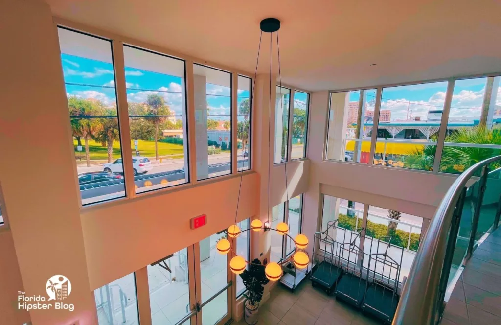 The Avalon Hotel in Clearwater with a view from the she second story in lobby with windows wrapped all around and hanging chandelier. Keep reading to discover more about the Avalon Club Hotel Clearwater Beach. 