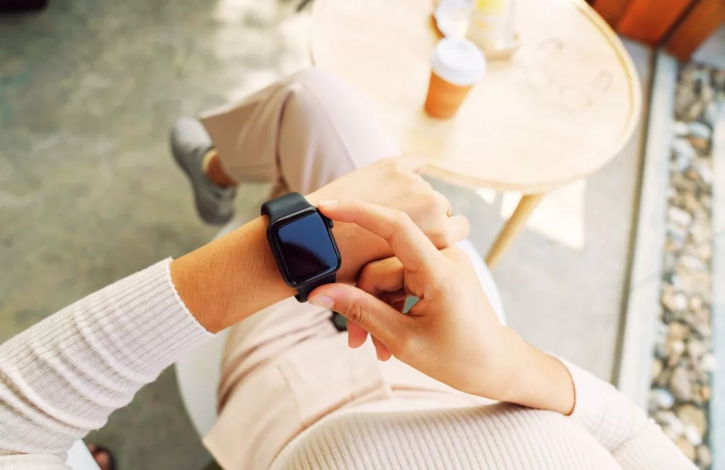 Lady with apple watch next to coffee. Keep reading to get the best watch travel cases and boxes.