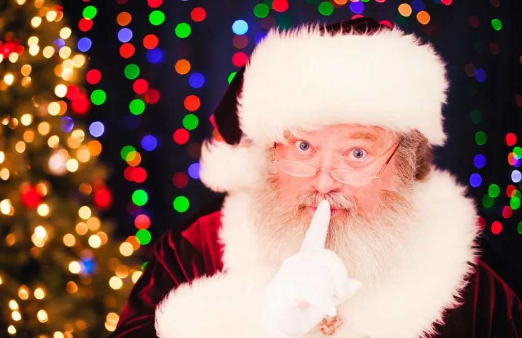 Santa with christmas lights sparkling behind him. Keep reading to discover more Christmas in Orlando events.