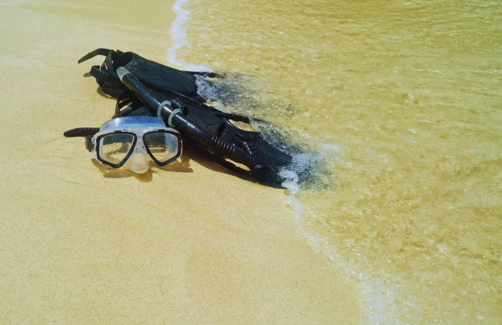 Black Snorkel Gear laying on the shore. Keep reading to get the Full Guide to Snorkeling in Panama City Beach, Florida.