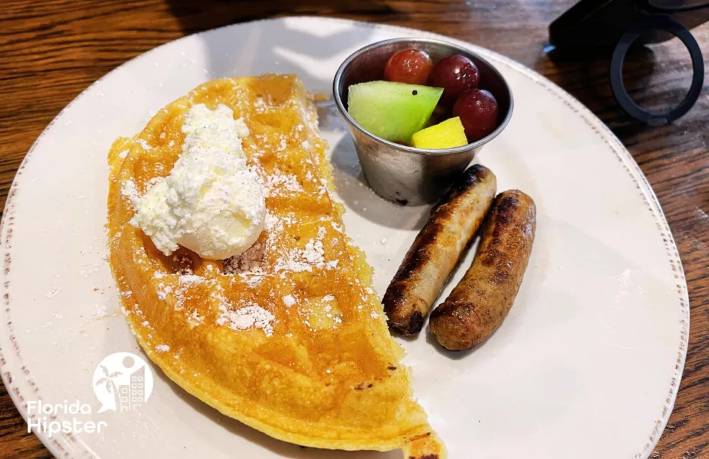 Kids Menu Half Waffle sausage and fruit at First Watch Breakfast and Brunch Restaurant. Keep reading to learn more about the best place to eat in Panama City Beach, Florida.