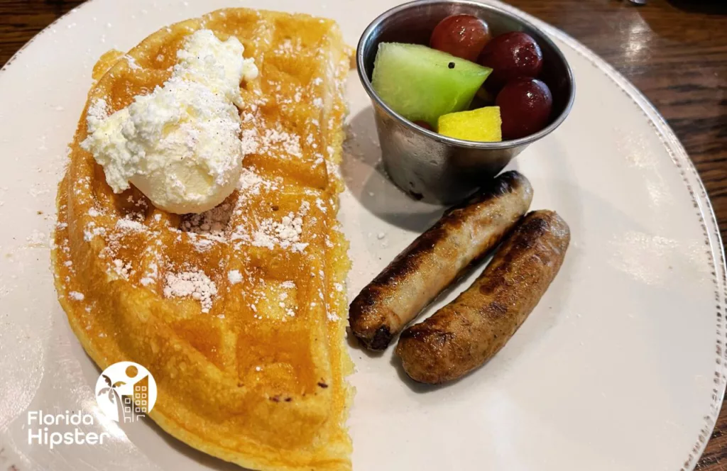 Kids Menu Half Waffle sausage and fruit at First Watch Breakfast and Brunch Restaurant. Keep reading to discover the best breakfast in Orlando.