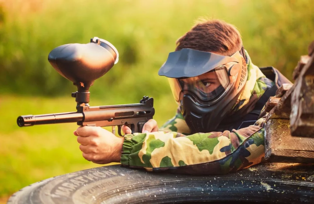 Warrior Sports Park with guy perched over tire playing game. One of the Best Paintball Fields in Orlando, Florida. Keep reading to discover all you need to know about the best paintball fields in Orlando, Florida.